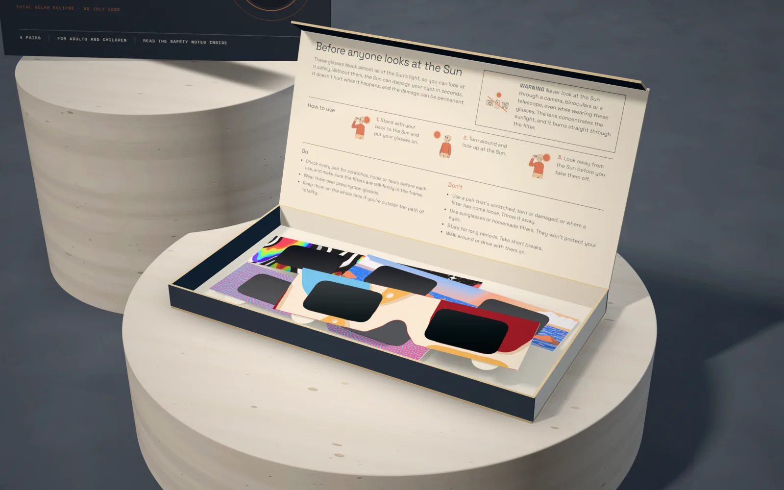 Close-up of the open family pack: the safety guide inside the lid and four pairs of eclipse glasses in different prints