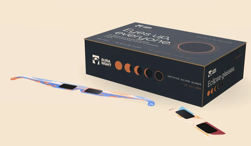A closed Aura Sight group box of certified eclipse glasses with two pairs beside it