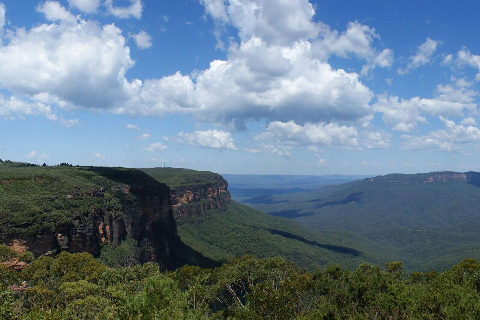 Sandstone cliffs and forested valley in the Blue Mountains, NSW, under blue sky and clouds