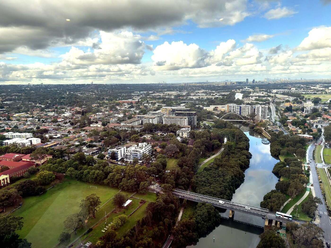 Aerial view over north-west Parramatta and the Parramatta River, with the Sydney CBD on the horizon